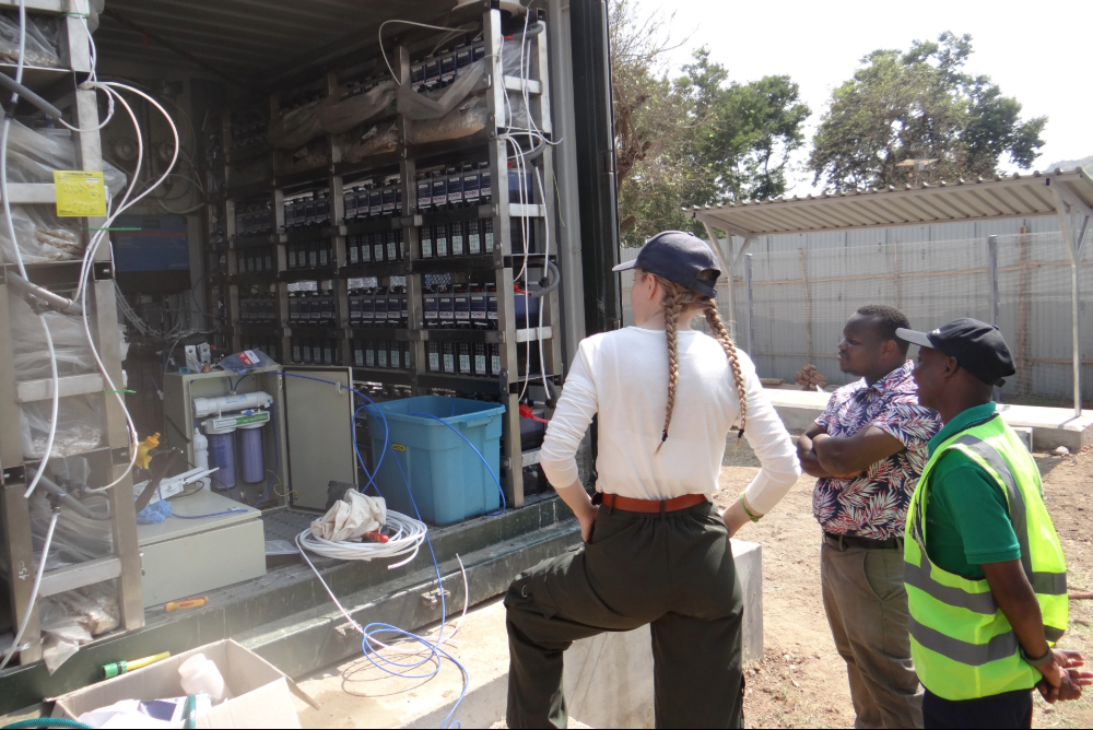 female engineer and two male engineers in front of battery-electrolyser test unit